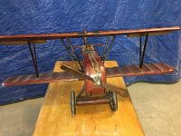Front view of the vintage wooden airplane model showing the two sets of wings, wooden propeller, and landing wheels.