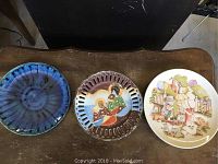 Overview of three unique decorative plates: one blue-toned ceramic, one pierced edge with Asian women design, and one with garden scene illustration.