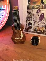 Photo showing front view of the vintage empty guitar-shaped liquor bottle with detached cork stopper shaped like the guitar's headstock.