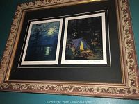 Angle view of the ornate framed print showing the two Tom Thomson scenes, with visible moonlight and campsite images.
