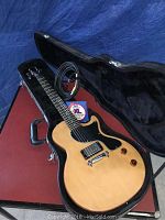 Guitar inside open case with cable and strings pack