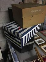 Three boxes likely containing hats stacked on each other; two boxes with striped design and one plain brown box labelled Walkers.