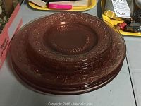 Stack of 4 pinkish-purple depression glass dinner plates showing decorative embossed patterns and translucent glass.