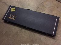 Closed view of black Westone branded hard guitar case on concrete floor.