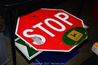 Stack of metal signs showing the red STOP sign on top with John Deere green oval sign beneath.