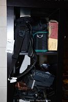 Shelving unit with camera cases, camera equipment, and accessories stacked and packed, showing the black cases with straps and various camera-related gear inside.