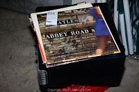 Stack of vinyl LP records including The Beatles Abbey Road album resting on top of a black Teac SL-A100 radio unit