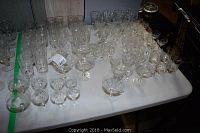 Full view of the assorted glasses on table with various sizes and shapes, clear glassware.