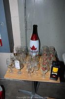 Photo of full set of mixed branded beer and wine glasses with Molson Canadian tall bottle on table