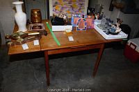 Full view of wooden drop leaf table with leaves open showing overall condition and surface wear.