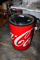 Full view of Coca Cola cooler showing red body with white logo and black lid.