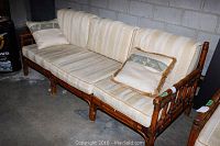 Full view of rattan sofa with cushions and pillows showing overall condition.