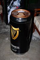 Frontal view of Guinness beer can shaped fridge showing logo, size, and scratches.