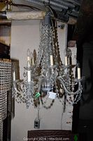 Full view of the crystal chandelier hanging from ceiling showing several curved arms and crystal bead strands.