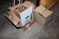 Overall view of two open cardboard boxes containing multiple beer glasses packed in divided sections.