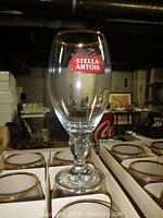 Single Stella Artois beer glass showing clear glass with logo and gold rimmed edge standing on top of original packaging boxes.