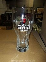 Single clear glass showing Alexander Keith’s Fine Beers logo with stag head