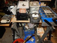 Overview of bench belt sander, hardware organizers on sawhorses and milk crate below
