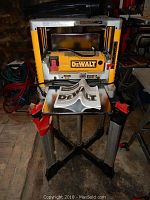 Front view of Dewalt 12.5" thickness planer on portable stand with instruction manual