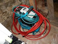 Overall photo of the Makita air compressor with coiled red and blue hoses, compressor visible in the basement corner.