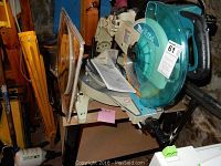 Makita slide compound miter saw mounted on metal stand showing blade guard and sliding rails