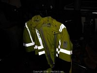Two large yellow and black Solarcity reflective safety suits hanging on a metal clothing rack. Reflective stripes clearly visible.