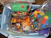 Tote holding multiple ziplock bags of assorted Lego pieces and K'Nex rods and connectors