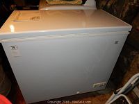 Front and side view of white GE chest freezer with closed lid showing overall condition and GE logo.