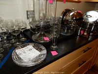 Glassware including Waterford crystal plates, wine glasses, pitched, bowl, and carafe arranged on a countertop