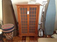 Front view of light brown wooden cabinet with Plexiglass doors and item number tag attached.