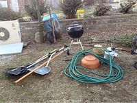 Full lot arranged on lawn showing Weber BBQ grill with garden tools including shovels, rakes, wheelbarrow, watering cans, and hose.