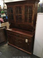 Full view of two-piece solid wood hutch with glass door upper cabinet and multiple drawers below.