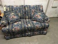 Front view showing two floral cushions and overall floral fabric upholstery.