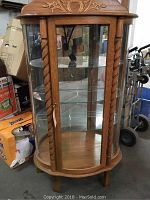 Front view showing curved oak cabinet with glass front panels, interior glass shelves and mirrored back