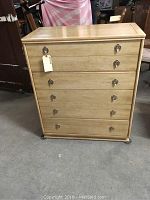 Front view of the solid blonde wood 5-drawer chest showing the handles and finish.