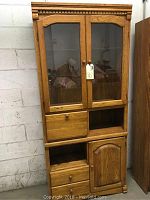 Full front view of oak curio cabinet showing glass doors, drawers, and cupboard below.