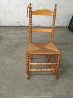 Front view of vintage turned maple rocking chair with woven reed seat in good condition.