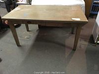 Front view of rectangular wooden work table showing two drawers and worn tabletop surface.