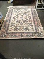 Full view of the floral pattern Milliken rug with a cream background and pastel flower motifs.