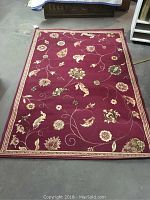 Full view of rust colored Wilton rug with floral pattern and cream borders on floor