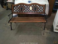 Front view showing cast iron frame, wooden slatted seat, lattice backrest with pineapple medallions