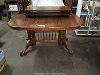 Full view of oak dining table with oval top, paw feet, and carved edges, showing overall shape and support structure.