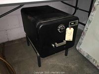 Black Sentry fire floor safe on metal stand, showing front with combination dial and electronic keypad