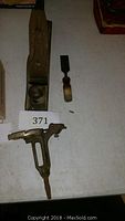 Overview photo of wood plane, chisel and threader tool laid out flat on a surface with lot number 371 card