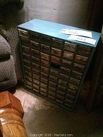 Full front view of the blue metal hardware sorter with small transparent drawers.