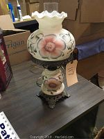 Full image of oil lamp style table lamp showing floral glass shade, metal base, and chimney