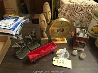 Full lot on table showing mixed decorative items including model train car, bookends, sculptures, clock, miniatures.
