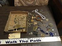 Overview shot of entire lot showing multiple costume jewelry items including necklaces, rosaries, watch, bracelets, and brooches.