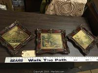 Three ornate framed oil on board paintings displayed with a ruler for scale.