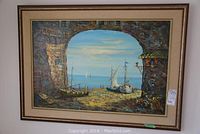 Full view of the framed oil on canvas showing a seascape through a stone arch with boats on shore and sea beyond.